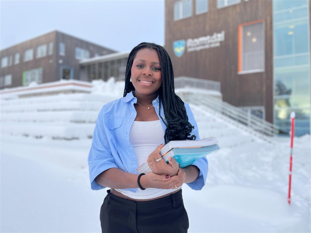 Bilde av kvinne som står ute i snøen framfor eit bygg